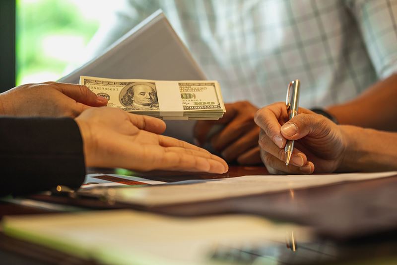 A desk with a banking consultant handing out money.